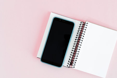 Notebook and smart phone on pink background. Mock up.の写真素材