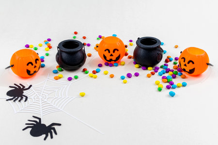 Halloween, pumpkins, colored sprinkles, cauldron, spider web silhouette and paper spiders, on white background. Select focus.の写真素材