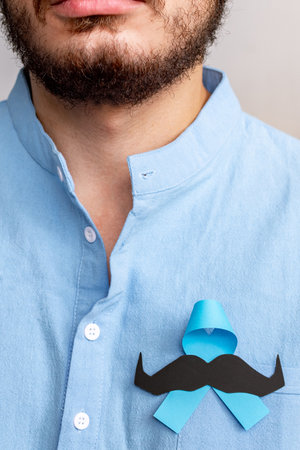 Man in blue shirt with Blue Ribbon and paper mustache for supporting people living and illness.の写真素材