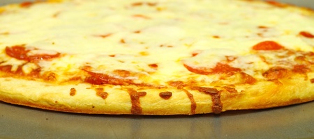 A fresh baked extra Pepperoni and extra Cheese Pizza Pie on the pie pan using a shallow depth of field and selective focusの写真素材