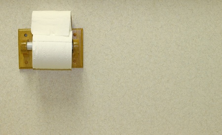 A wooden toilet paper holder mounted on a textured wall with an extra roll of toilet paper on top with room for your text.の写真素材