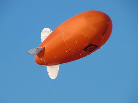 Orange Inflatable Advertising Blimp Zeppelin, Airship on the Blue Backgroundの写真素材