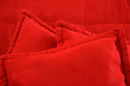 Three red cushions on red comfortable sofa.の写真素材