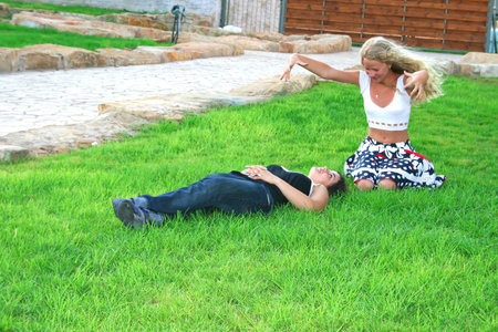 Blond and brunette girls having fun on the grass.の写真素材