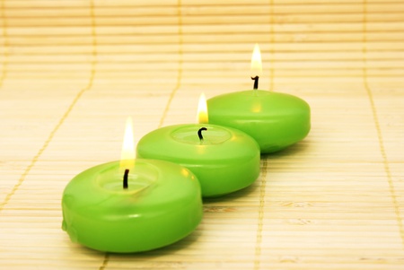 Green candles on bamboo background.の写真素材