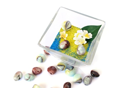 Vase with colorful sand, stones and flowers on white background.の写真素材