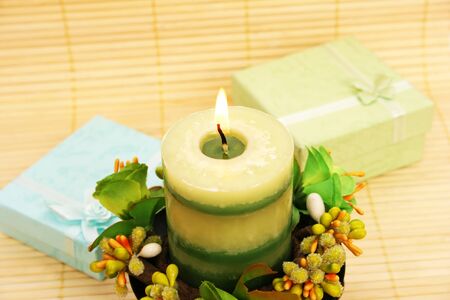 Candle, flowers and present boxes on bamboo background.の写真素材
