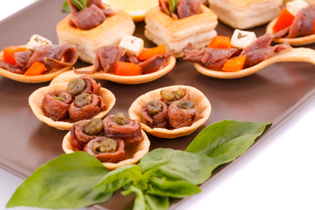 Anchovies in pastries, basil on brown plate.の写真素材