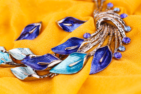 Stylish necklace and earrings on yellow fabric background.の写真素材