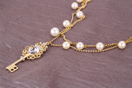 Stylish necklace with pearls and key on fabric background.の写真素材