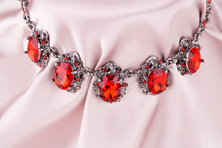 Stylish necklace with red stones on a pink fabric background.の写真素材
