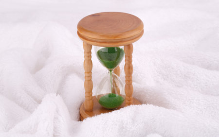 Sandglass on white towel, closeup picture.