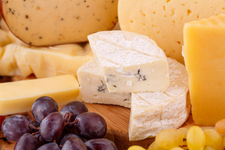 Various type of cheese and grapes closeup picture.