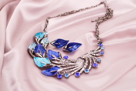 Stylish necklace and earrings on pink fabric background.の写真素材