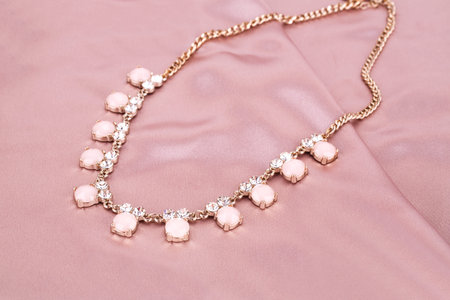Stylish necklace with stones on pink fabric background.の写真素材