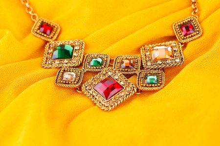 Stylish necklace with colorful stones on yellow fabric background.の写真素材