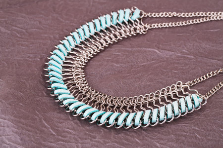 Stylish necklace on fabric background.