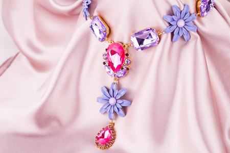 Stylish necklace with colorful stones on pink fabric background.の写真素材