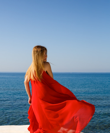 Pretty blond woman in the red dress at the beach in Cyprus.の写真素材