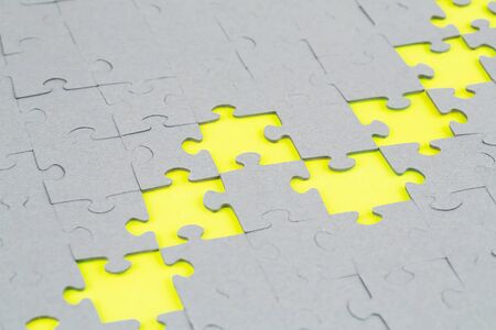 Unfinished jigsaw puzzle pieces on yellow background.の写真素材