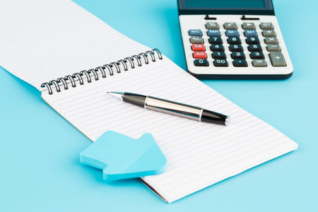 Calculator, pen and notepads on blue background.