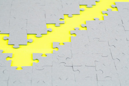 Unfinished jigsaw puzzle pieces on yellow background.