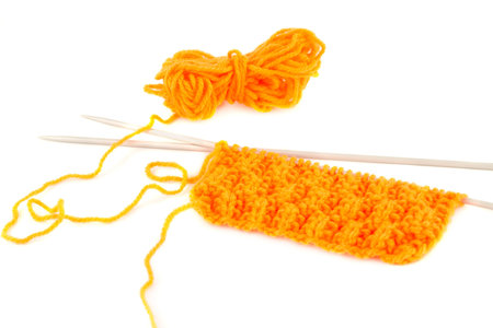 Yellow yarn with knitting needles on white background.