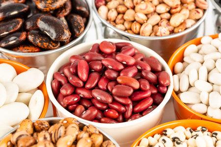 The collection of different beans in the colorful buckets.