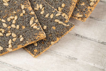 Pile of crackers with poppy and sunflower seeds on gray wooden background.の写真素材