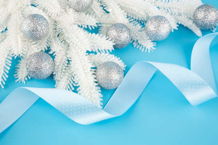 Christmas decoration with gray balls, ribbon and fir-tree white branch on the blue background.の写真素材
