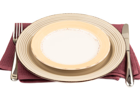 Two empty plates, knife and fork on purple cotton towel on white background.の写真素材