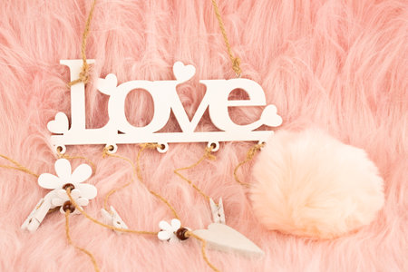 White wooden word love and fluffy ball on pink fur background.の写真素材