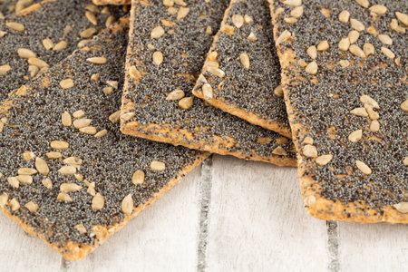 Pile of crackers with poppy and sunflower seeds on gray wooden background.の写真素材