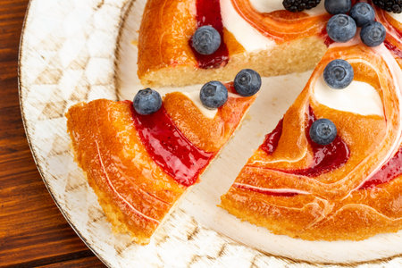 Berries pie with blueberries and blackberries on wooden plate on brown background.