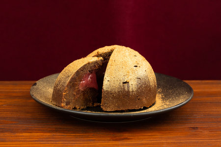 Belgian chocolate sponge with a cherry filling and gold glitter on black plate. Christmas cake on...