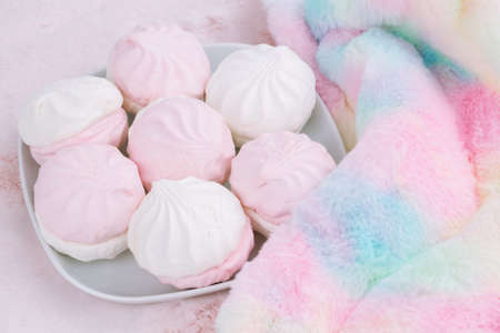 Russian dessert zefir or zephyr on white plate and colorful fur scarf on pink background. Marshmallow closeup picture.の写真素材