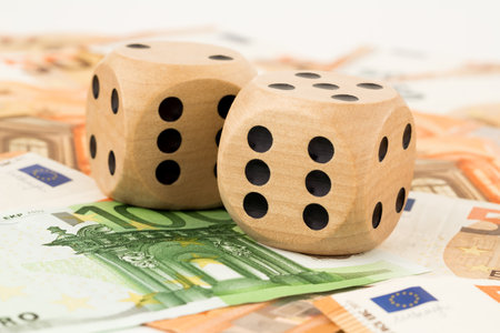 Two wooden dices on many euro money banknotes background.の写真素材
