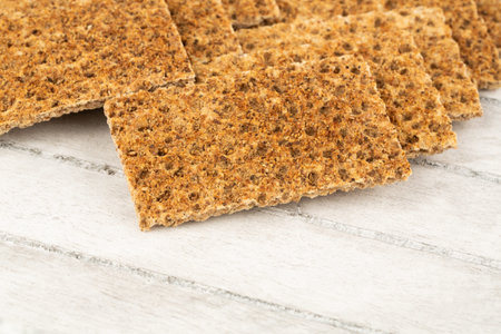 Pile of crackers with spices on gray wooden background.