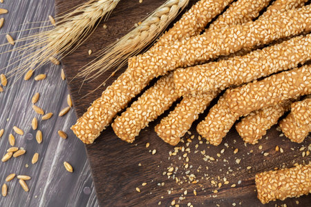 Bread sicks with sesame seeds on wooden board.