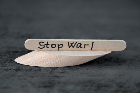 Stop war text on the wooden long board on the gray background. Stop war words against the agression.
