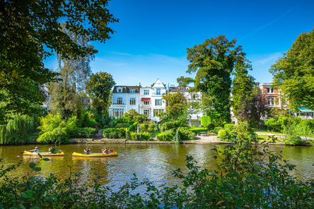 The house at the river, people boating on the river in sunny summer day. The beautiful houses at the river in Hamburg, Germany.の写真素材