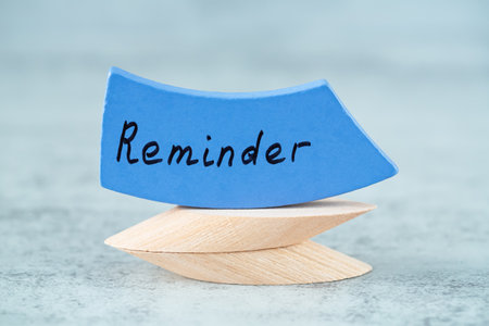 Reminder word written with black letters on the blue wooden board on the gray background. Motivation word.の写真素材