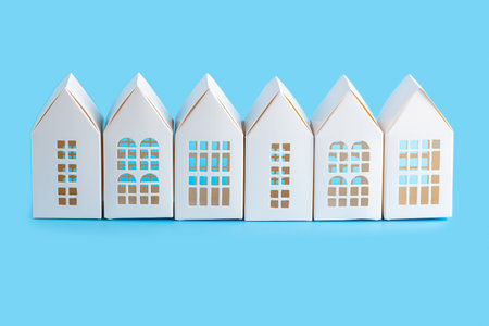 Six white paper houses isolated on blue background.の写真素材
