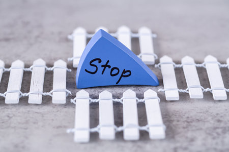 Stop word written with black letters on the blue wooden board in the middle of white wooden small...