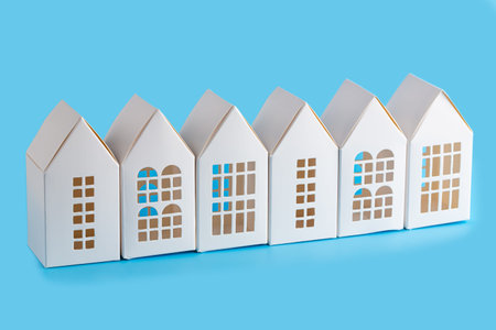 Six white paper houses isolated on blue background.