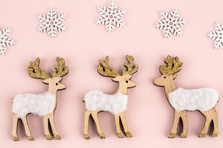 Deer family wooden toys and white snowflakes  on pink background. Christmas deer toys decoration.の写真素材