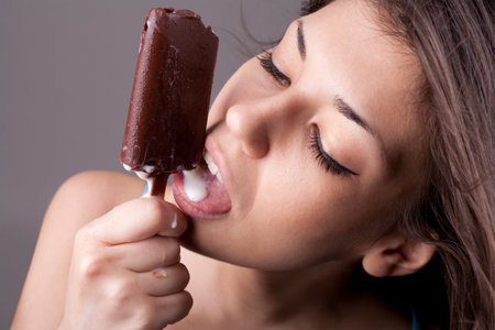 Sexy brunette woman eating chocolate ice cream. Studio shot