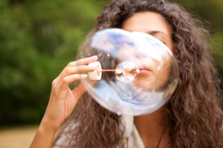 Beautiful woman in the park playing in bubbles cup. Outdoor portrait.