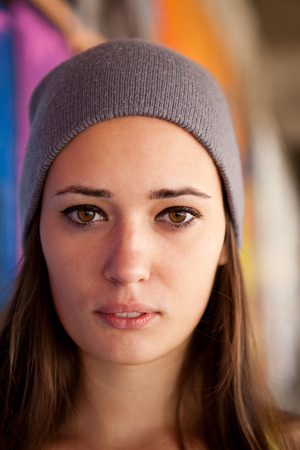 Pretty girl with gray hat in front of graffiti wall. Outdoor portrait.の写真素材