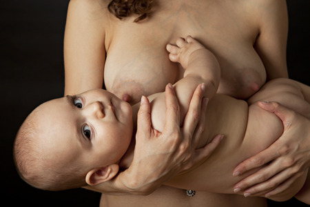 Mother breastfeeding her baby. Studio shot. Black background.の写真素材